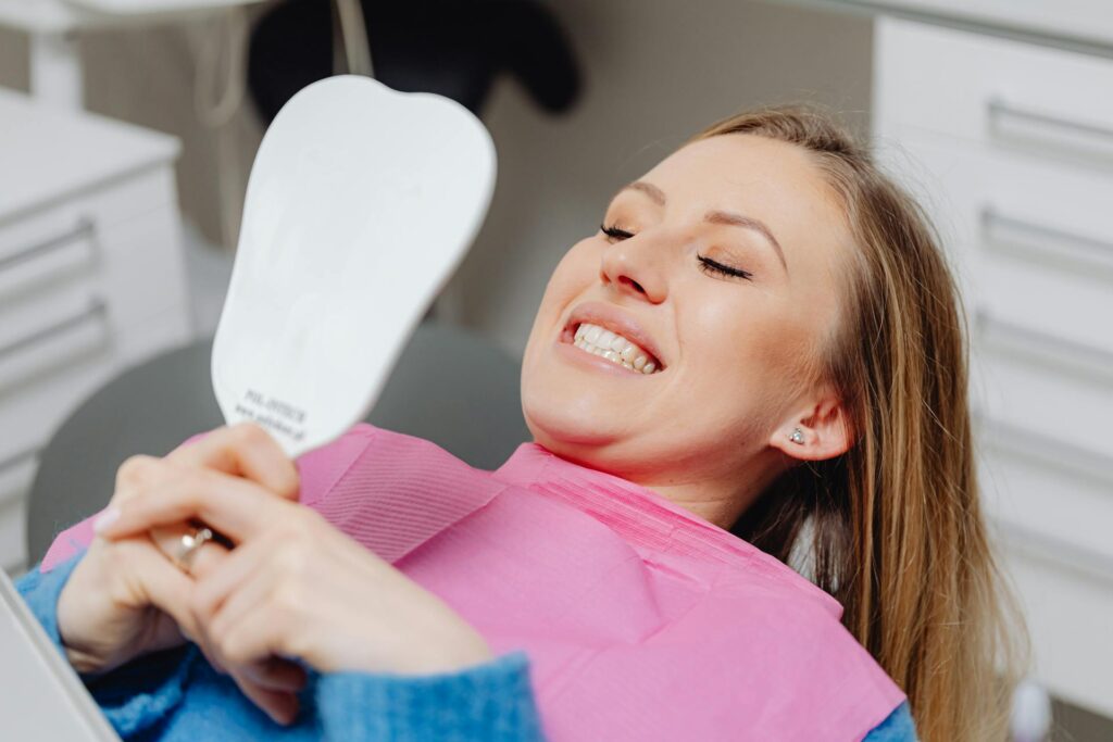 A patient looking at her teeth in a hand-held mirror