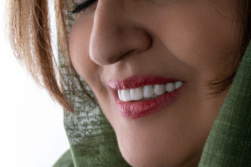 A close-up of a woman smiling and showing off her neat, bright teeth