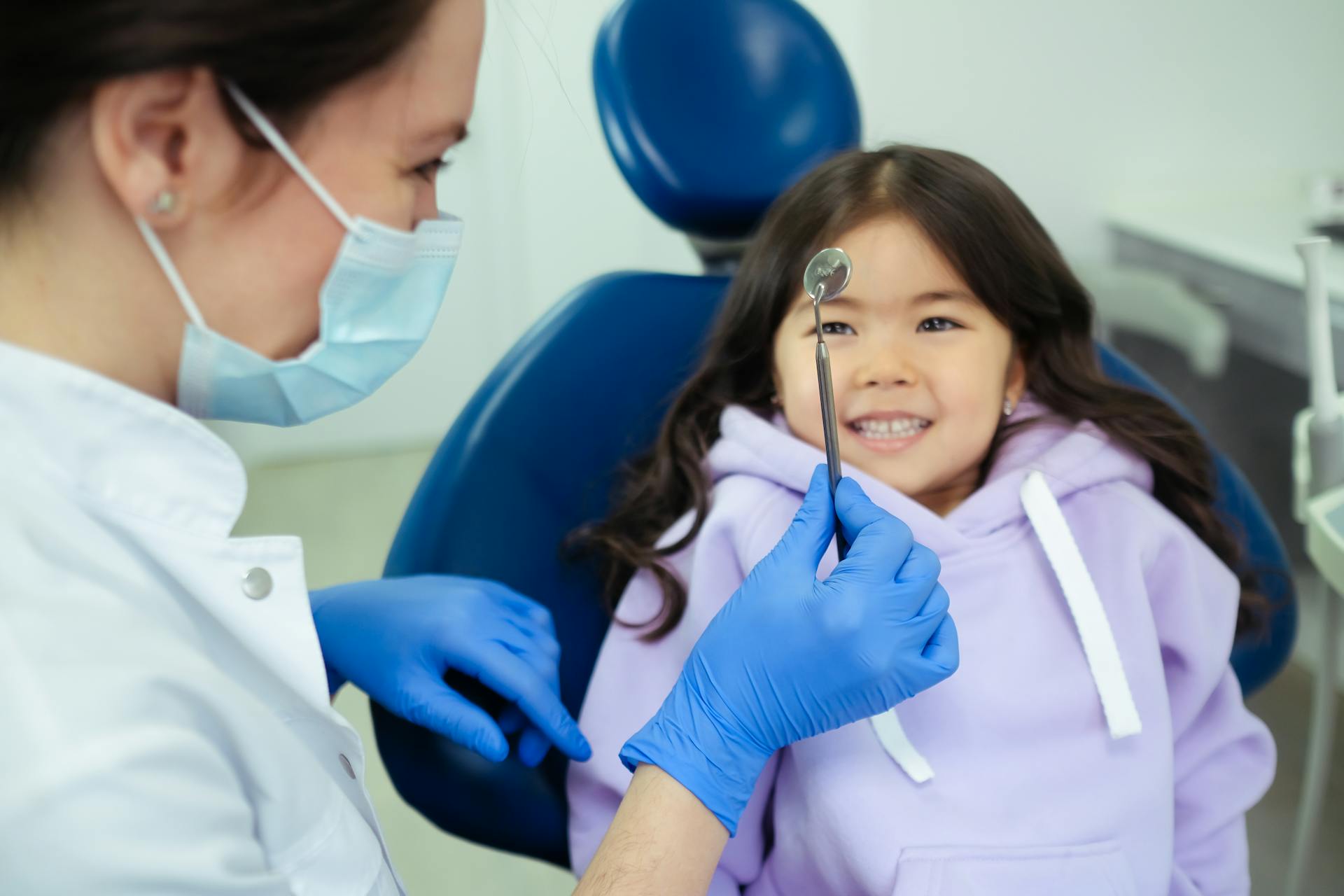 A dentist showing a mouth mirror to a child